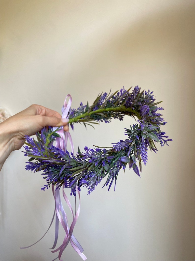 May include: A purple lavender flower crown with a light pink ribbon tied at the back.