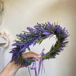 May include: A purple lavender flower crown with a green stem and two long purple ribbons.