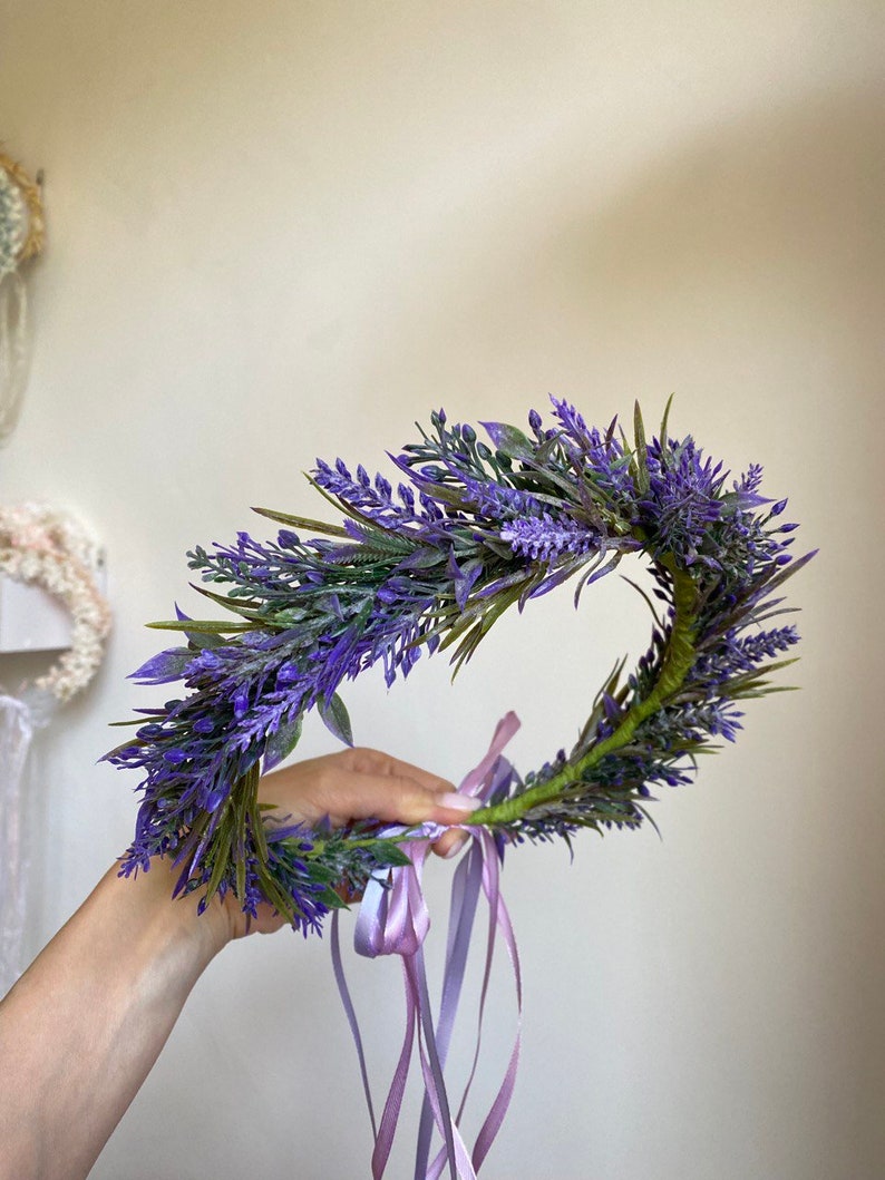 May include: A purple lavender flower crown with a green stem and two long purple ribbons.