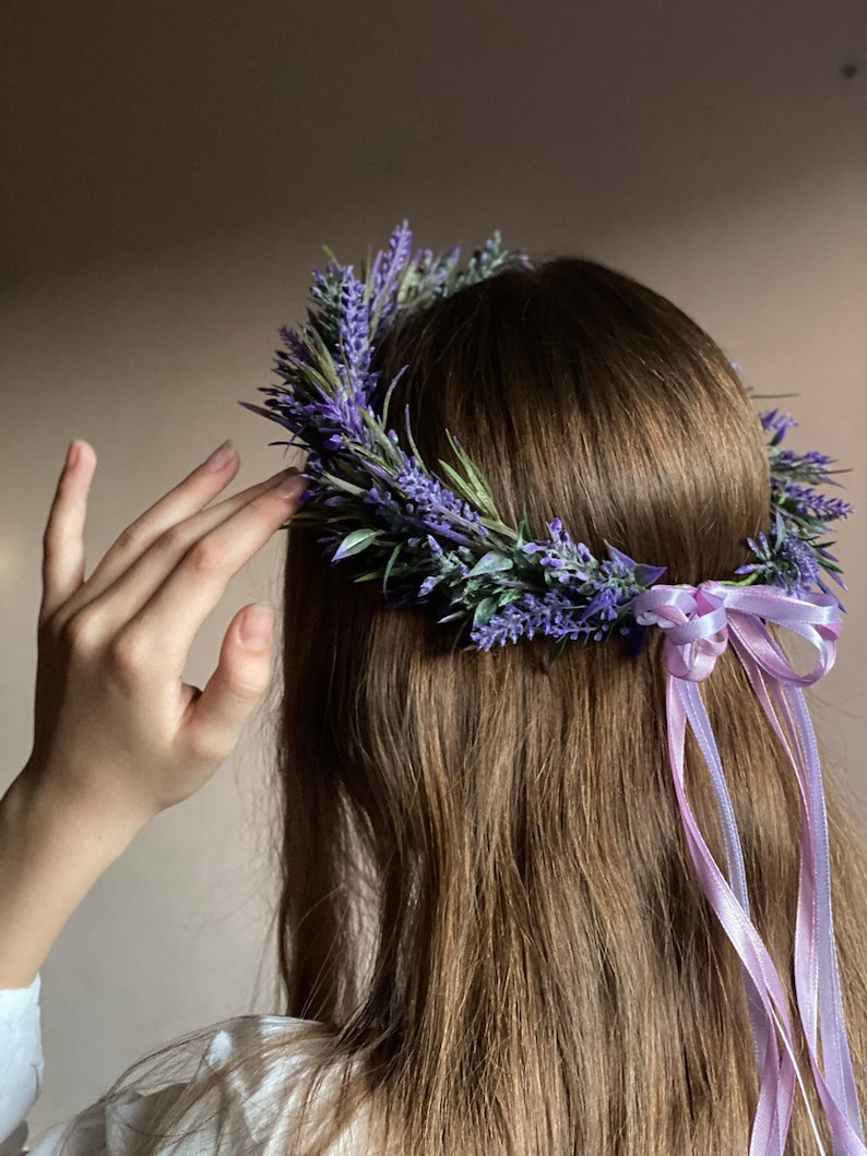 May include: A lavender flower crown with a purple ribbon tied at the back. The crown is made of fresh lavender flowers and greenery.