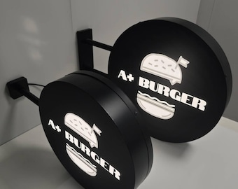 May include: Two black round signs with white text and a white burger graphic. The signs say "A+ BURGER" and are attached to black metal arms.