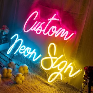 May include: Custom Neon Sign with the words "Custom" in pink, "Neon" in blue, and "Sign" in yellow.
