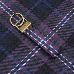 May include: A purple, blue, and green plaid keychain with a brass key ring.