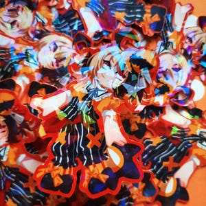 May include: A collection of colorful holographic stickers featuring a cartoon character wearing a black and white striped outfit with a yellow and orange bow. The character has blonde hair and is wearing a black and white hat.
