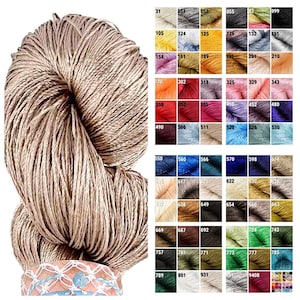 May include: A skein of beige linen yarn with a colour chart showing a variety of colours. The chart includes numbers for each colour.