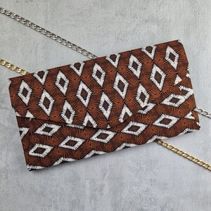 May include: A brown and white patterned clutch with a gold chain strap. The clutch has a geometric design with diamonds and stripes.