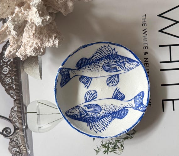 A tiny hand-sculpted coastal fish ring dish that's quirky, tactile, and under $8 — the kind of charming little object you'd actually stop and pick up.