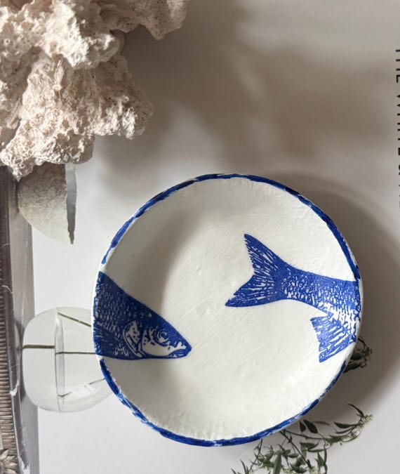 A tiny handmade coastal fish ring dish that actually has personality — the quirky seaside character makes it a conversation-starter on any nightstand.