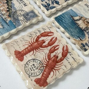 Peut inclure: Un ensemble de quatre dessous de verre carrés en céramique aux bords festonnés, arborant des motifs de timbres postaux vintage. L'un présente deux homards rouges, un autre une scène côtière marquée Bodrum Turkiye, et un autre des motifs floraux bleus.