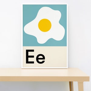 Peut inclure: Une impression d'art imprimable bleue et blanche avec un jaune d'œuf jaune au centre d'un œuf blanc. L'impression a la lettre "Ee" en texte noir en bas.