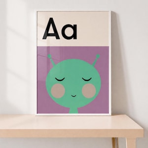 Peut inclure: Une affiche encadrée présentant la lettre Aa en noir en haut sur un fond crème. En dessous, une section violette affiche un personnage extraterrestre vert avec les yeux fermés, un petit sourire et des joues roses rondes, centré.