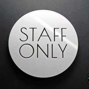 May include: White round sign with black text that reads "STAFF ONLY".