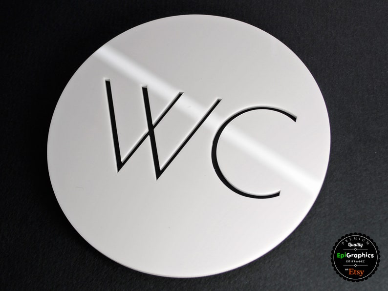 May include: White round sign with black lettering that says "WC" for a restroom.