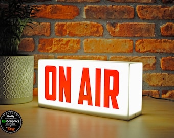 May include: White rectangular sign with a red "ON AIR" message. The sign is illuminated from behind, creating a bright glow.