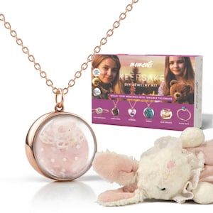 May include: A rose gold necklace with a round pendant that has a pink and white lace design inside. The necklace is part of a DIY jewelry kit called "Moments Keepsake DIY Jewelry Kit" that allows you to mold your memories into tangible talismans.