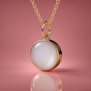 Op de afbeelding: Een gouden ketting met een ronde hanger met een witte maansteen.
