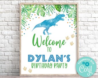 Op de afbeelding: Een printbaar welkomsbord voor een dinosaurusthema-verjaardagsfeest. Het bord heeft een blauw dinosaurus-silhouet, groene bladeren en kleurrijk confetti. De tekst op het bord luidt "Welkom op Dylans verjaardagsfeest".