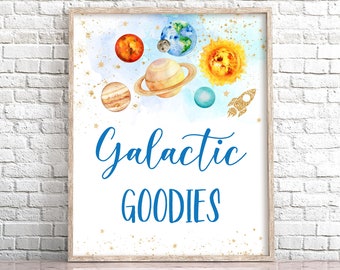 May include: A printable sign with a watercolor background featuring planets, stars, and a rocket ship. The text "Galactic Goodies" is written in blue cursive font.