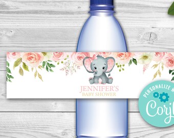 Può includere: Etichetta per bottiglia d'acqua con un design floreale rosa e bianco e un adorabile elefante grigio con un fiocco rosa. L'etichetta dice "Baby Shower di Jennifer" e ha un logo per il sito web "Corjl" per personalizzare l'etichetta.
