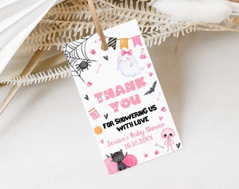 May include: A rectangular Halloween-themed gift tag with a pink and white design. The tag features a spiderweb, a ghost, a bat, and the text "Thank You for Showering Us with Love". The tag is tied with a brown string.