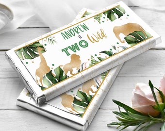 May include: Two chocolate bar wrappers with a jungle theme. The wrappers are white with gold and green accents. The text on the wrapper says "Andrew is Two Wild".