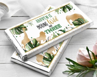 May include: Two chocolate bar wrappers with a jungle theme. The wrappers are white with gold and green accents. The text on the wrapper reads "Andrew is young and wild and three".
