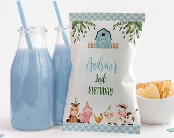 May include: A white party favor bag with a farm animal theme, featuring a horse, pig, chicken, sheep, and cow. The bag has the text "Andrew's 2nd Birthday". Two glass bottles with blue liquid and straws are on the left.