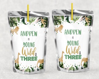 Könnte beinhalten: Zwei silberne Saftbeutel mit grünen und goldenen Dschungeltiermotiven. Der Text auf den Beuteln lautet "Andrew is Young Wild & Three".