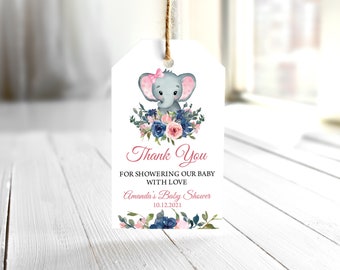 May include: Thank you for showering our baby with love. Amanda's Baby Shower 10.12.2021. A white tag with a pink and blue floral design and a cartoon elephant with a pink bow.