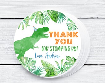 May include: Round thank you sticker with a green dinosaur wearing a blue party hat. The sticker has a green, white, and orange color scheme and says "Thank You for Stomping By! Love, Andrew".