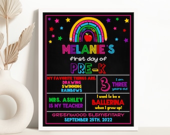 Könnte beinhalten: Ein farbenfrohes Schild aus schwarzer Tafel mit einem Regenbogen aus Bleistiften und einem roten Apfel. Das Schild lautet "Melanie's first day of Pre-K" und enthält Details über ihre Lieblingsdinge, ihr Alter und ihre Zukunftswünsche. Es enthält auch den Namen ihrer Lehrerin, den Namen der Schule und das Datum.