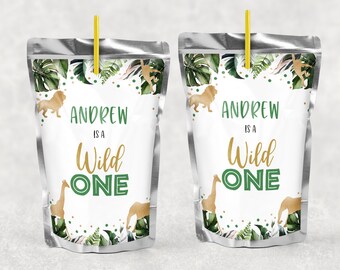 Könnte beinhalten: Zwei grüne und goldene Saftbox-Etiketten mit Dschungel-Motiv. Die Etiketten zeigen einen Löwen, eine Giraffe und einen Elefanten sowie grüne Blätter und goldene Konfetti. Der Text auf den Etiketten lautet "Andrew is a Wild One".
