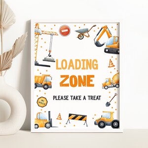 Może przedstawiać: Drukowana tabliczka z białym tłem i pomarańczowymi i czarnymi pojazdami budowlanymi. Tabliczka zawiera napis "Loading Zone" i "Please take a treat".