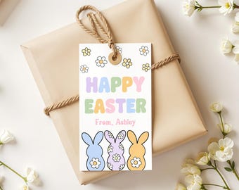 May include: A white gift tag with a colorful "Happy Easter" message and three pastel bunny illustrations. The tag is decorated with yellow daisy flowers and has the text "From, Ashley" at the bottom.