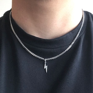 May include: A silver chain necklace with a lightning bolt pendant.