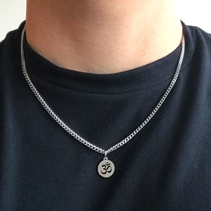 May include: A silver chain necklace with a round pendant featuring the Om symbol.