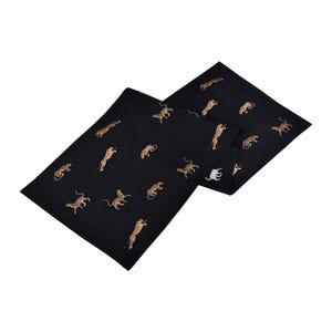Puede incluir: Un camino de mesa negro con estampado de guepardo dorado. El camino de mesa está hecho de una tela suave y lujosa y es perfecto para agregar un toque de elegancia a cualquier mesa.