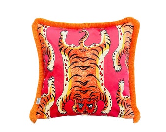 May include: A pink throw pillow with an orange fringe border features a repeating pattern of orange and black tigers. The tigers are depicted upside down with their paws in the air.