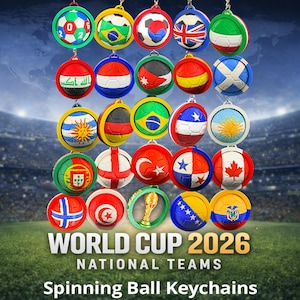 May include: A collection of spinning ball keychains featuring national flags, with the text "WORLD CUP 2026 NATIONAL TEAMS". The keychains are round, with a soccer ball design and a metal loop for attaching to keys. The background shows a stadium.