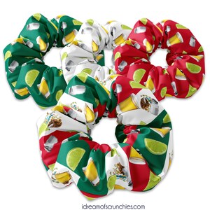 May include: Three colorful hair scrunchies with a Mexican flag design. The scrunchies feature a pattern of lime wedges, beer bottles, and salt shakers.