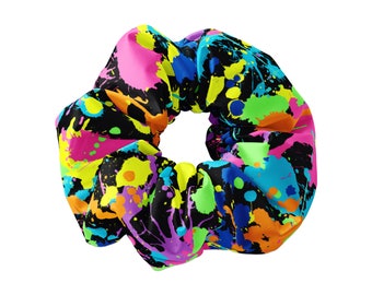 Könnte beinhalten: Ein schwarzes Haargummi mit einem bunten Farbklecks-Design. Das Haargummi hat leuchtende Farben wie Pink, Gelb, Grün, Blau und Orange.