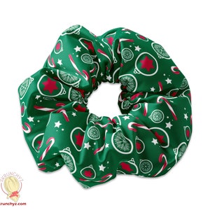 Könnte beinhalten: Grüner Scrunchie mit einem Weihnachtsmuster mit roten Kugeln, Zuckerstangen und weißen Schneeflocken.