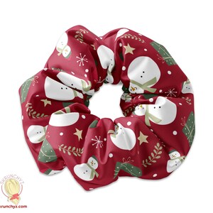 Könnte beinhalten: Ein roter Scrunchie mit einem weißen Schneemann- und einem grünen Weihnachtsbaum-Muster.