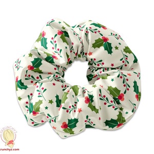 Könnte beinhalten: Ein weißer Haargummi mit einem festlichen Muster aus Stechpalmen und Beeren. Der Haargummi ist aus weichem, dehnbarem Stoff gefertigt und perfekt, um jedem Outfit einen Hauch von Weihnachtsfreude zu verleihen.