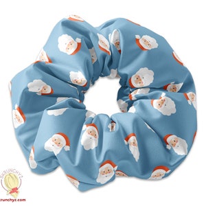 Könnte beinhalten: Ein blauer Haargummi mit einem sich wiederholenden Muster von Weihnachtsmann-Gesichtern. Die Weihnachtsmann-Gesichter sind weiß mit roten Mützen und weißen Bärten.