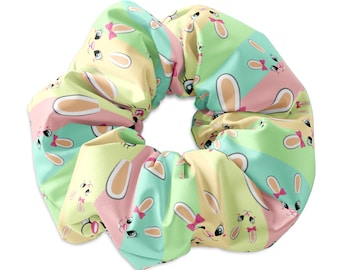 May include: A pastel green, pink and yellow scrunchie with a repeating pattern of bunny faces. The bunnies have pink bows and white ears.
