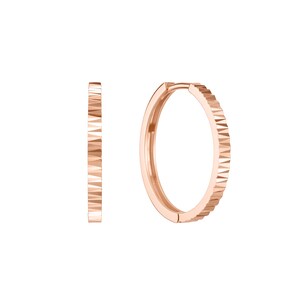 May include: A pair of rose gold hoop earrings featuring a textured, geometric pattern along the outer edge. The design consists of a series of small, repeating triangular facets that create a faceted appearance on the circular metal bands.