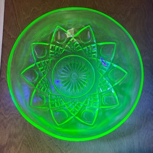 May include: A vintage green glass bowl with a geometric pattern. The bowl has a starburst design in the centre and a scalloped edge.