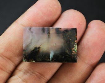 May include: A rectangular polished gemstone featuring a translucent pale pink and white base with deep black dendritic inclusions and scattered metallic copper-colored flecks throughout the surface of the stone.