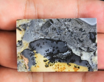 Puede incluir: Primer plano de una losa de ágata pulida, rectangular, con un patrón único de negro, gris, blanco y amarillo. El ágata tiene un aspecto natural y orgánico.